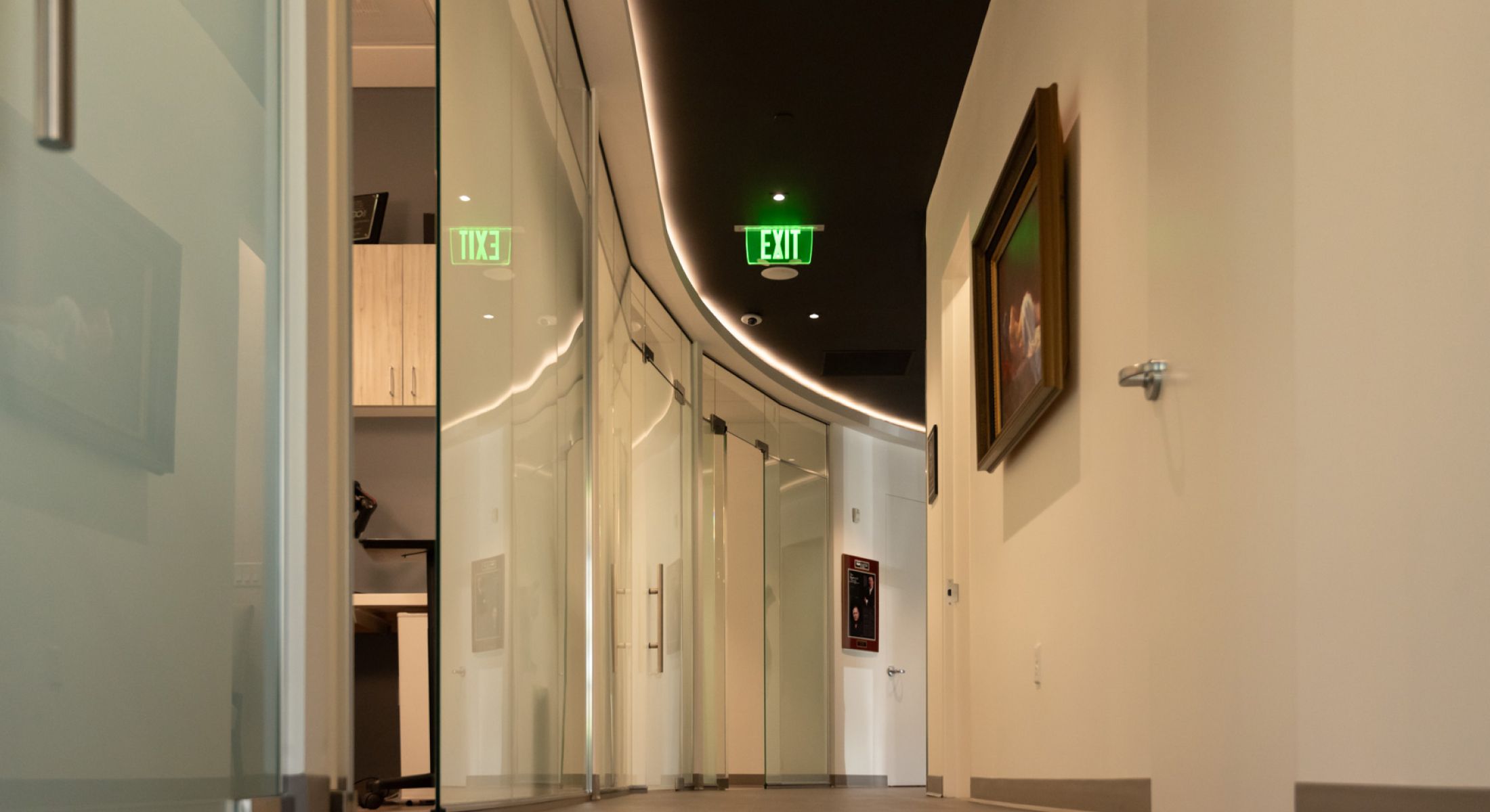 Modern hallway with glass doors and exit sign.