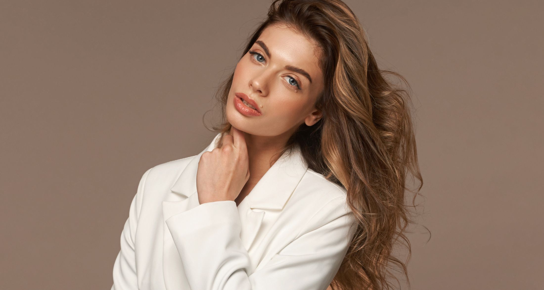 Woman in white blazer with long wavy hair.