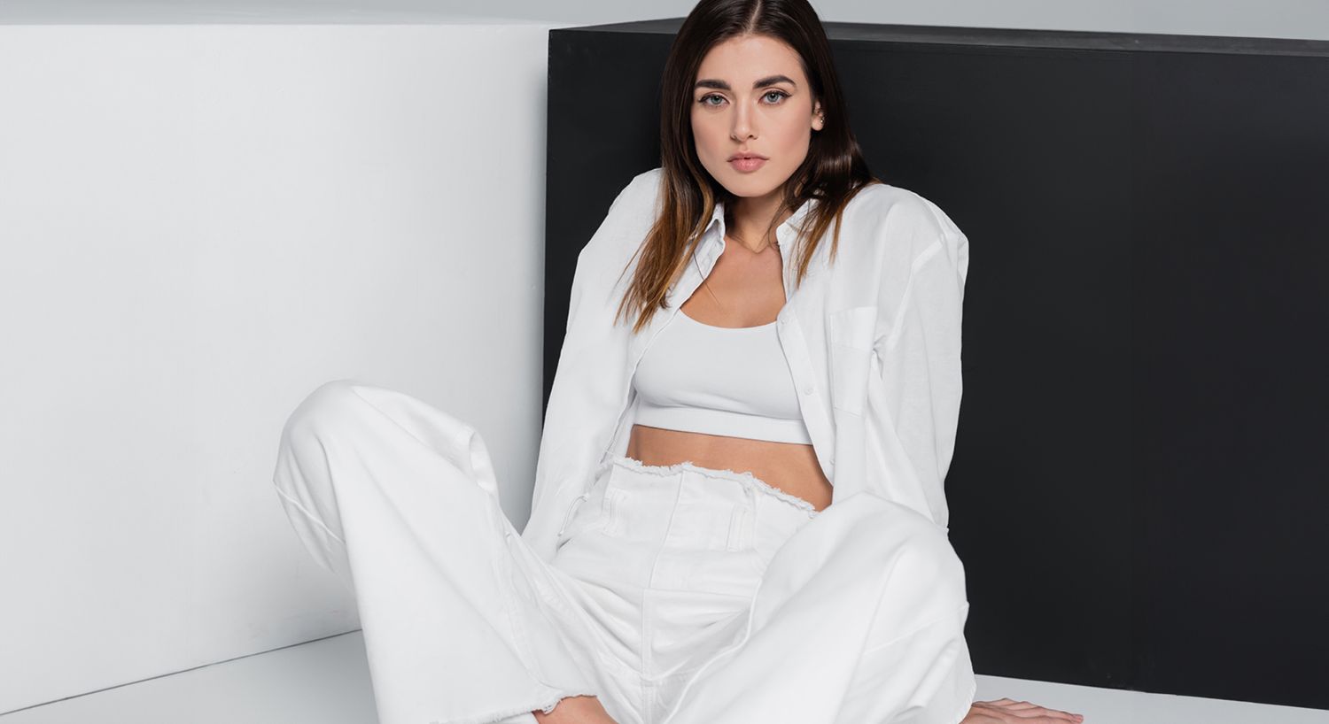 Model in stylish all-white outfit against minimal backdrop.