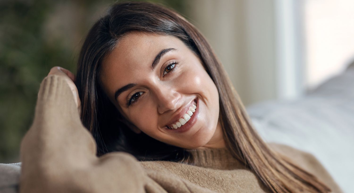 Smiling woman in a cozy sweater indoors.