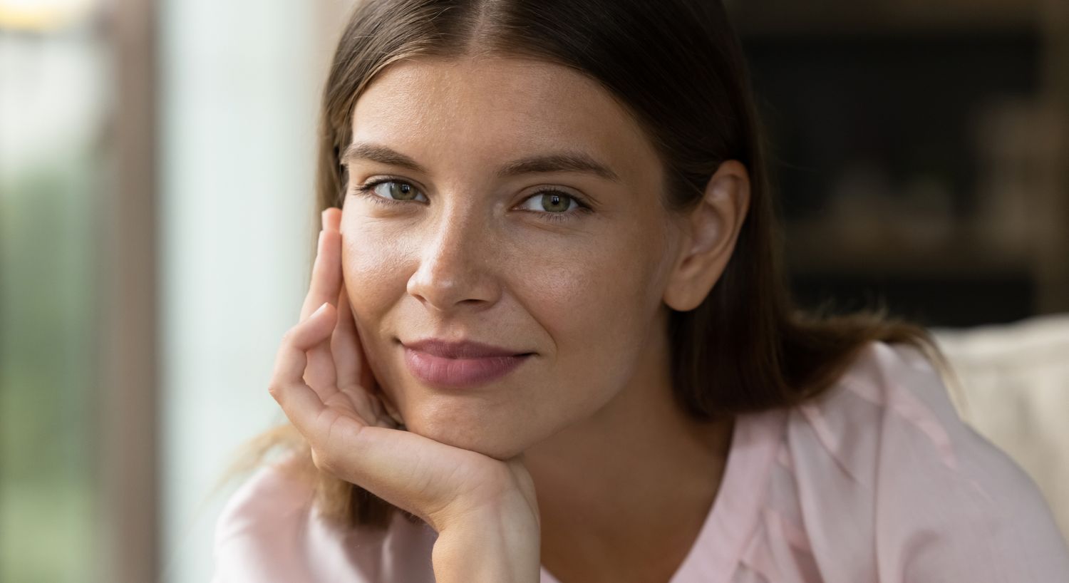 Woman resting her chin on hand, smiling gently.