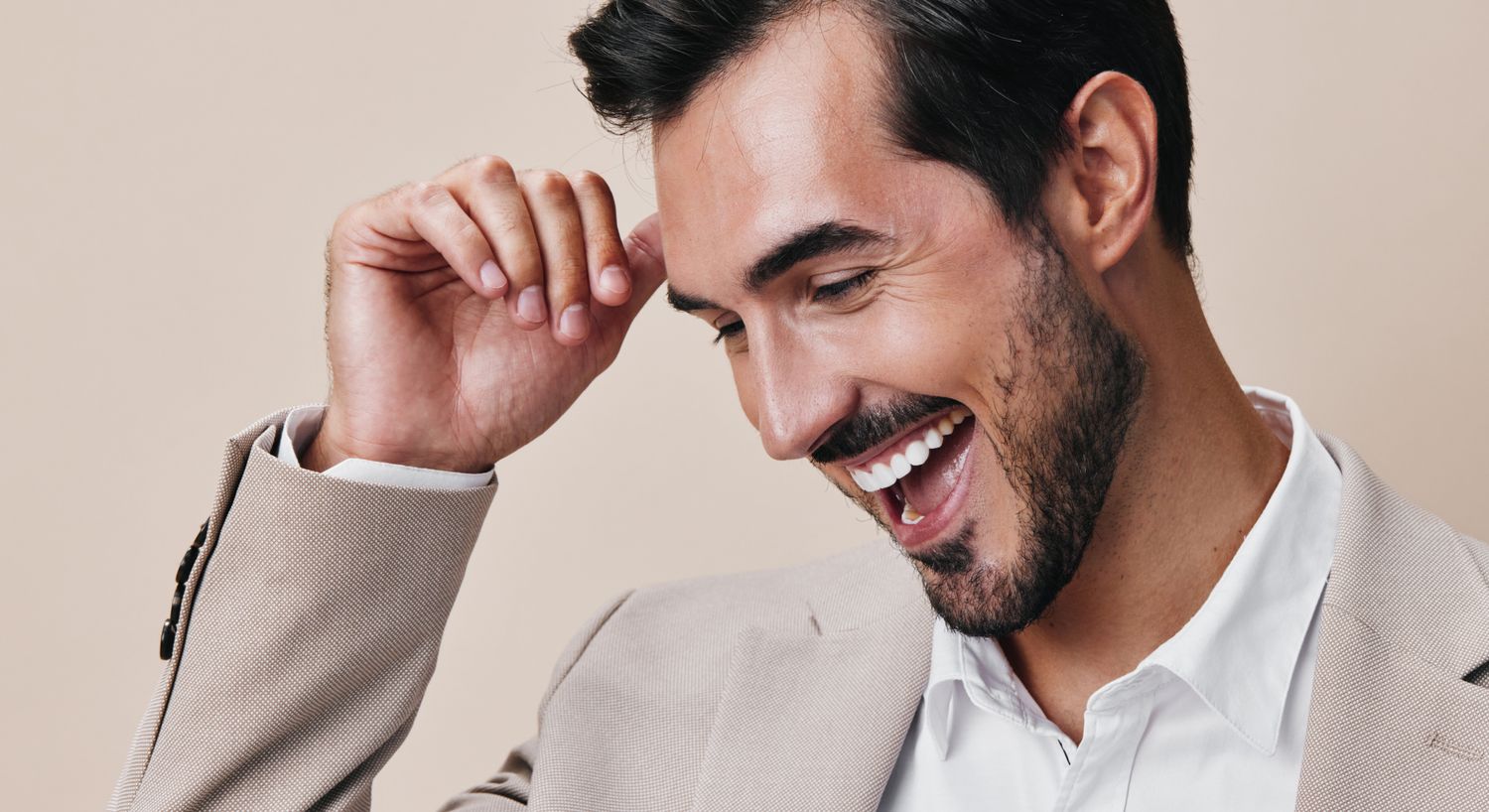 Smiling man in a light suit, joyful expression.