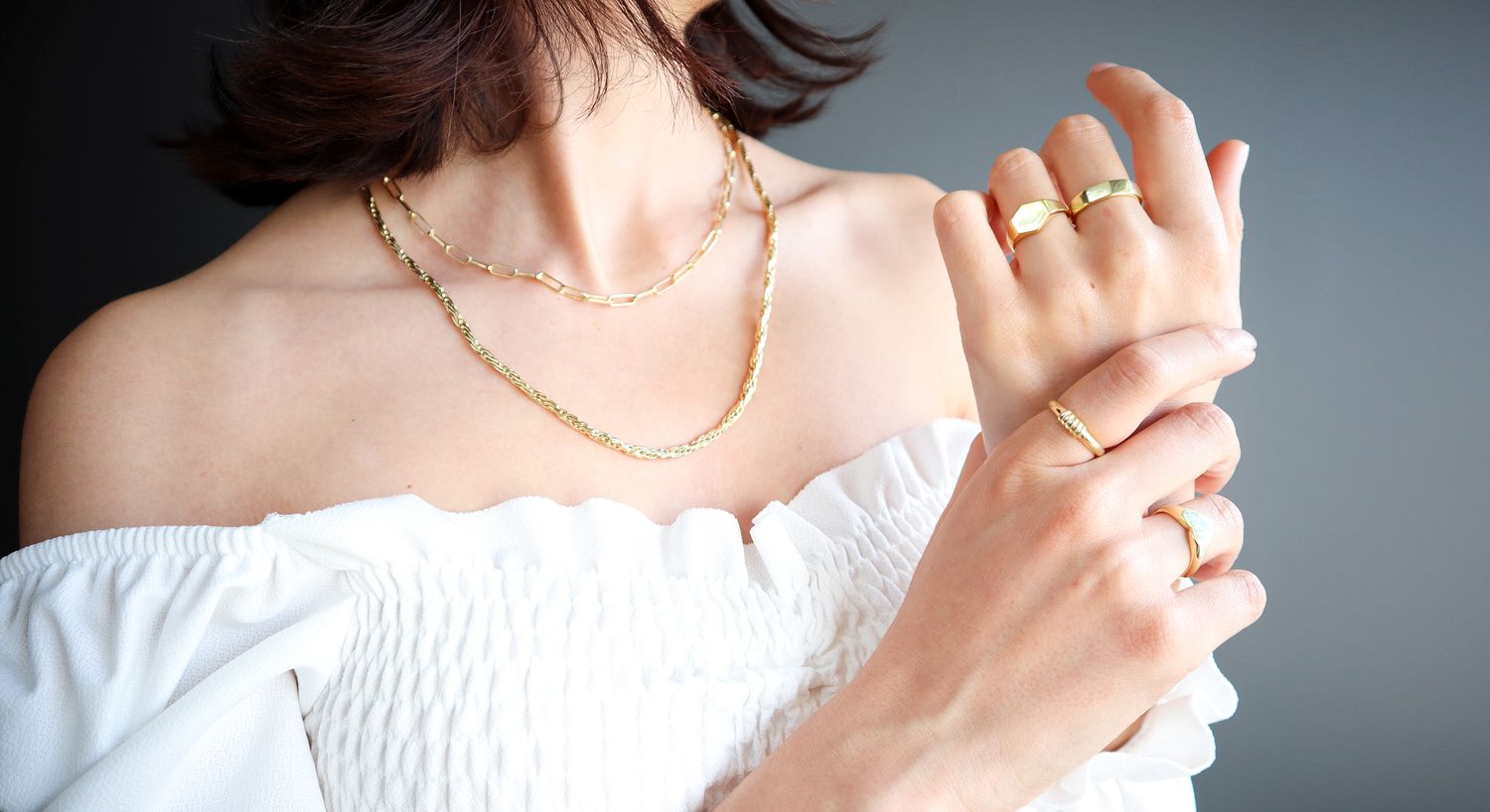 Elegant gold jewelry with white off-shoulder top.