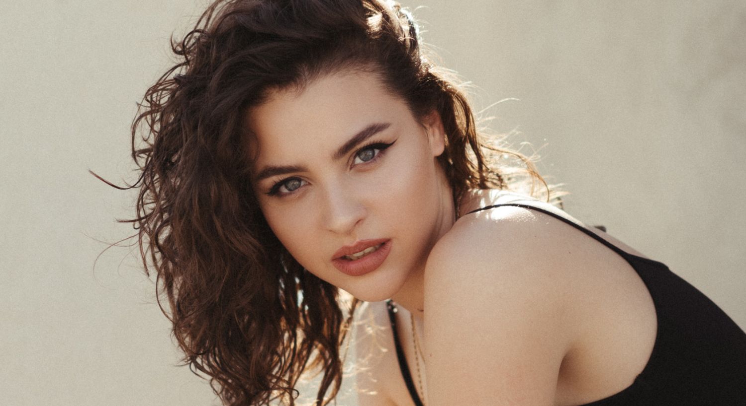 Young woman with curly hair and striking gaze.