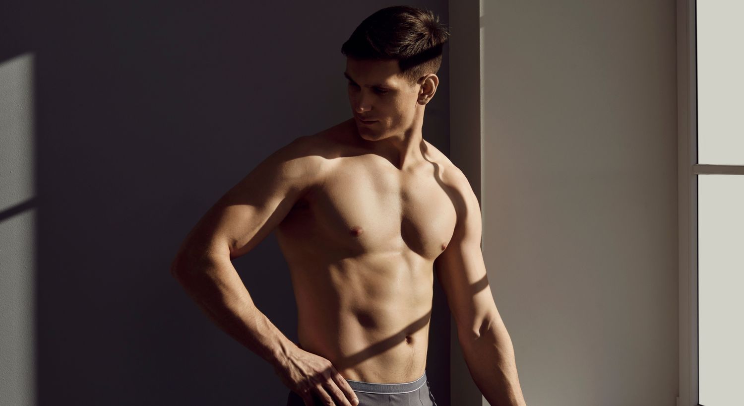 Athletic man posing in soft, dramatic lighting.