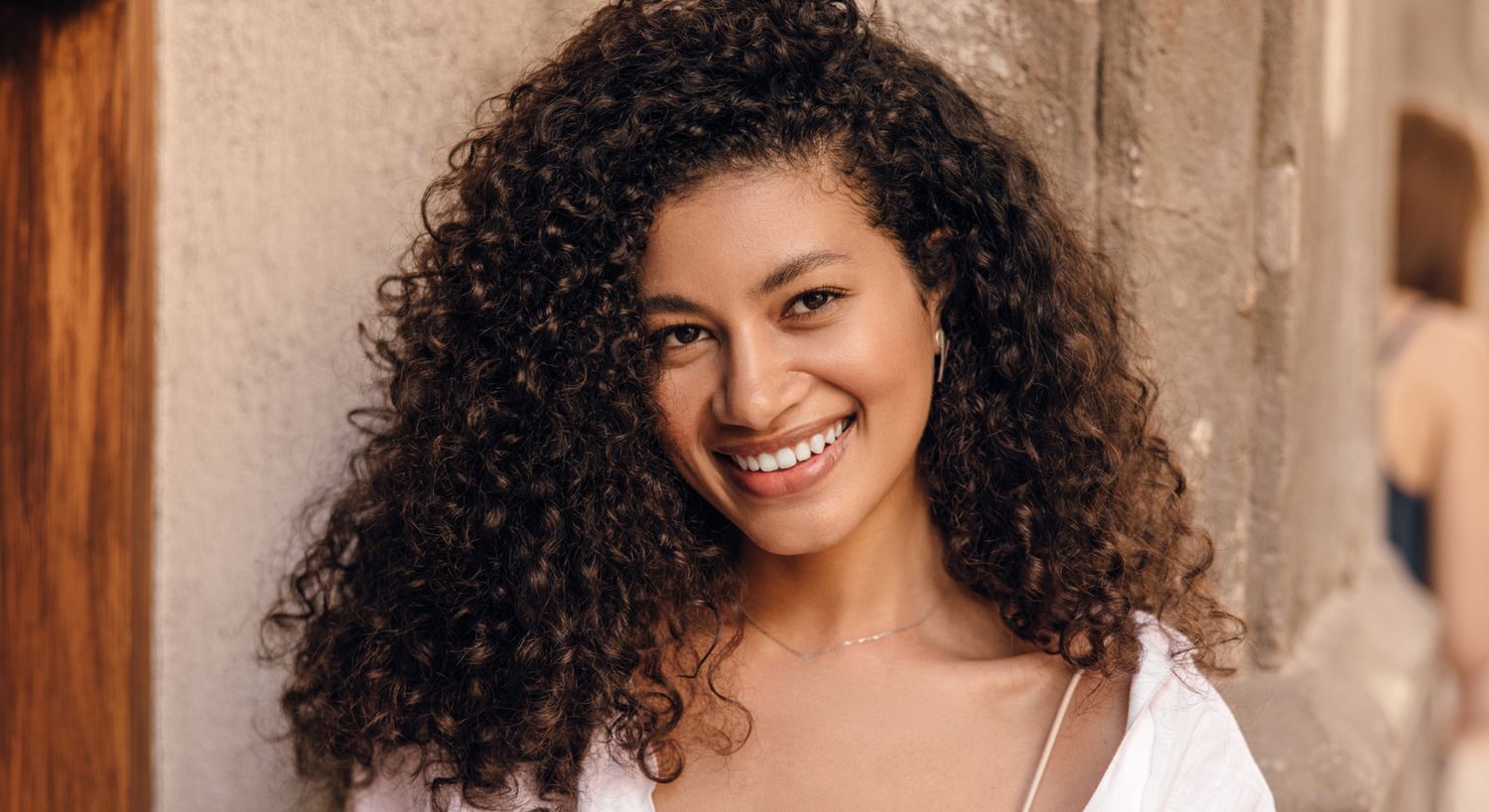 Smiling woman with curly hair outdoors.