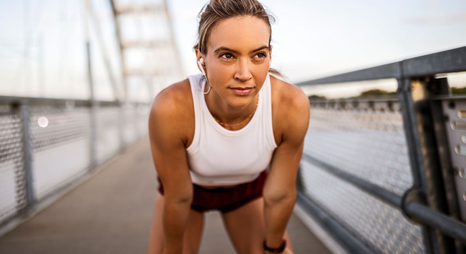 Athletic woman catching her breath on a bridge.